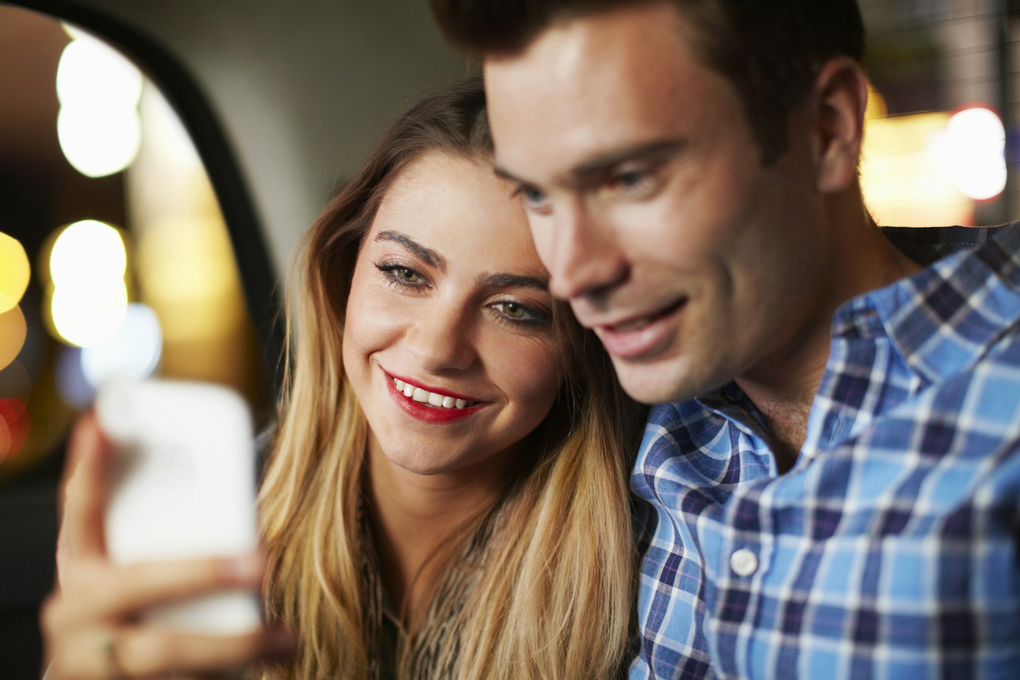 Couple looking at smartphone city taxi at night