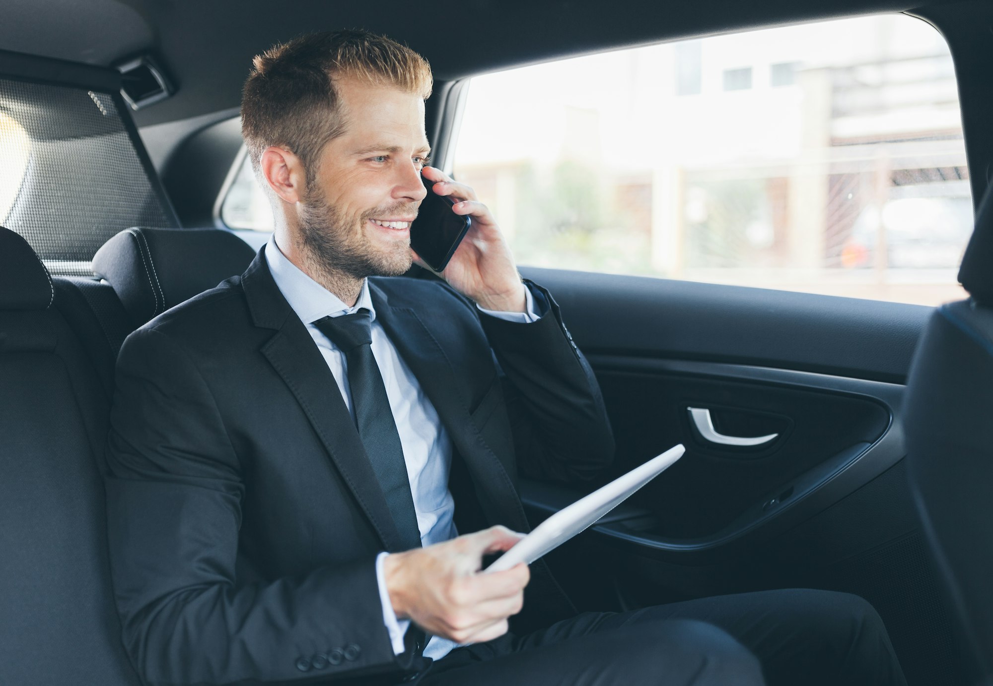 Executive businessman at the back of car using a mobile phone